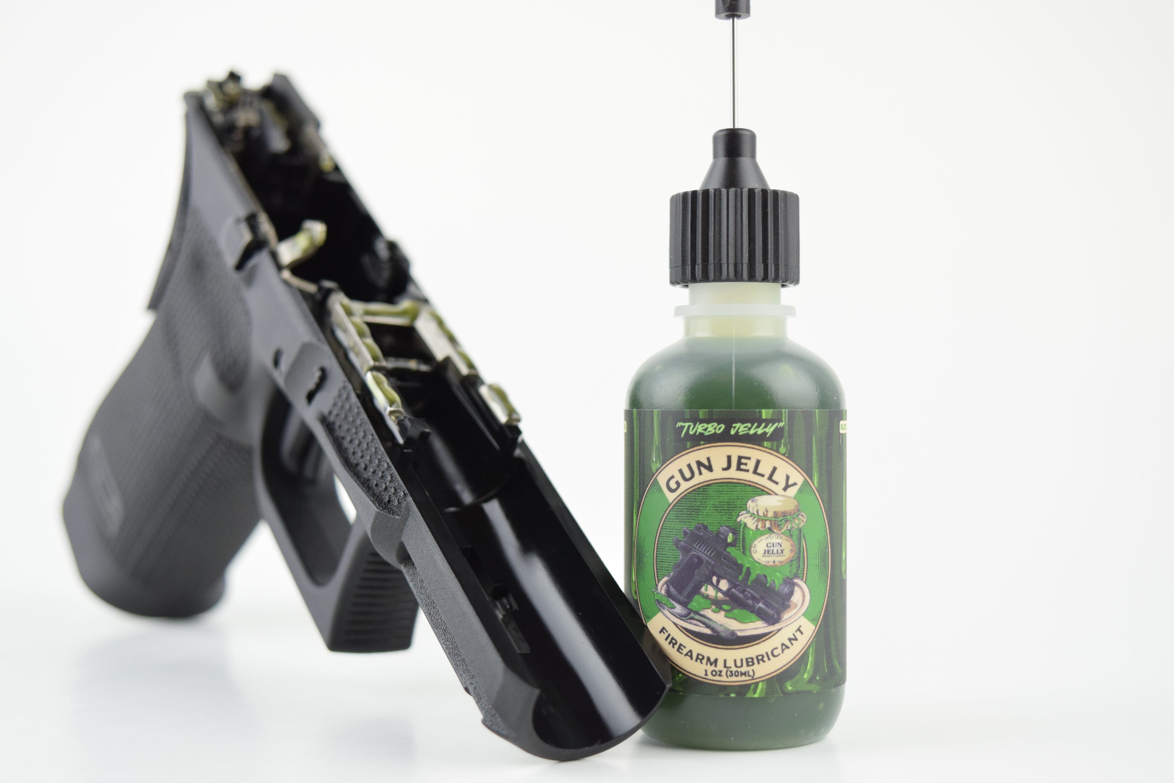 A bottle of Turbo Jelly Gun Jelly firearm lubricant next to a black handgun on a clean white background.