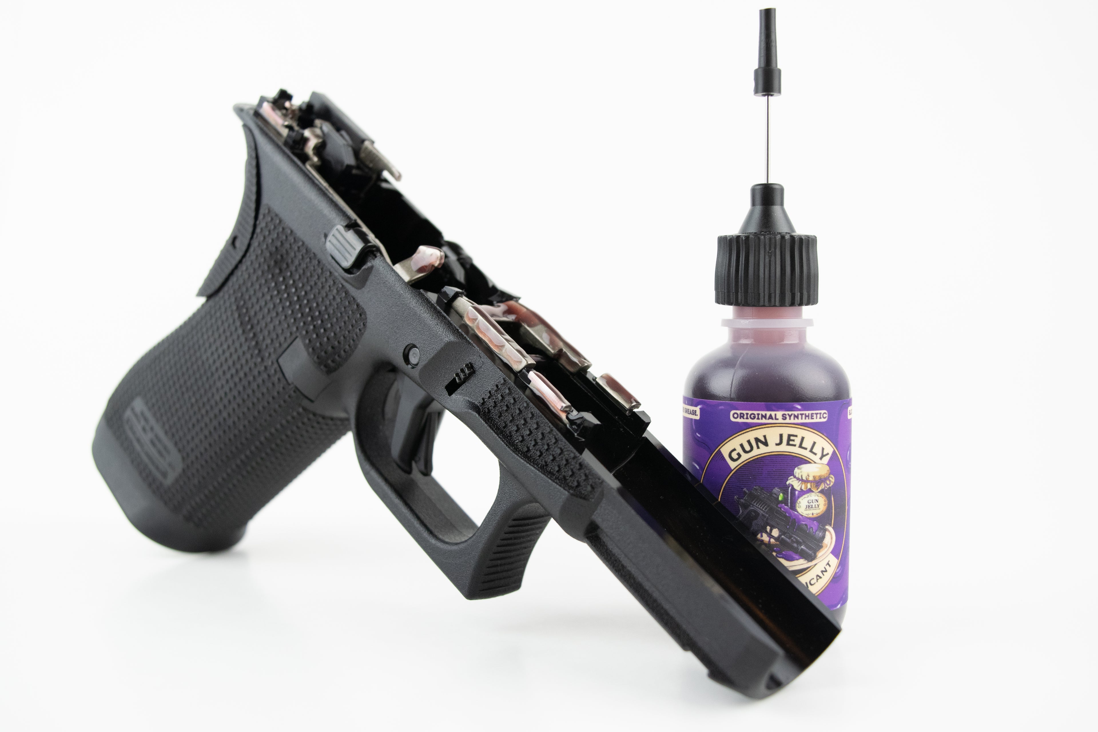 A black semi-automatic handgun shown open with the slide removed, positioned next to a small bottle labeled 'Gun Jelly' on a clean white background.