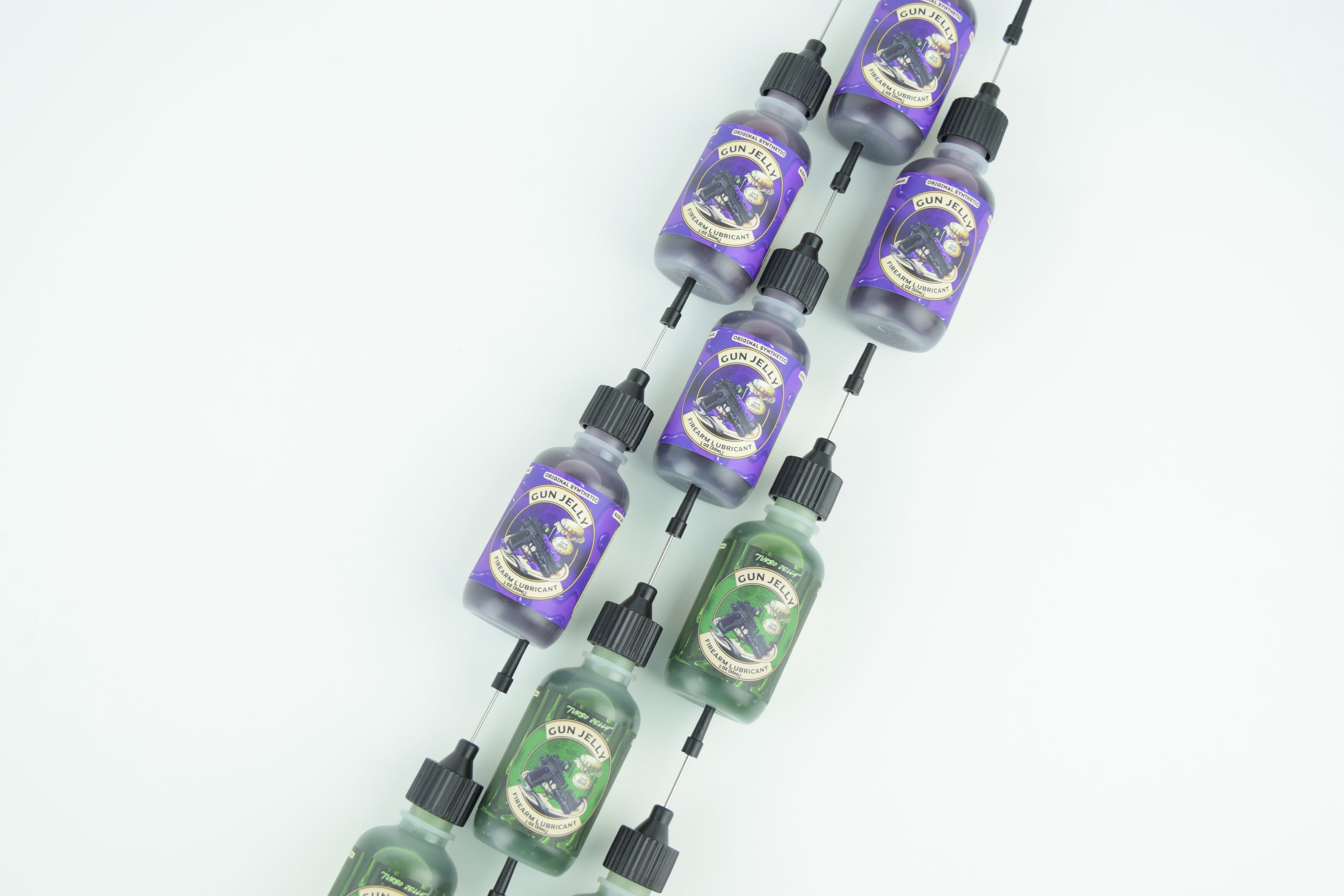Two strings of small dropper bottles threaded together diagonally on a white background. One string contains purple bottles with gold labels, and the other contains green bottles with gold labels, both with black caps.