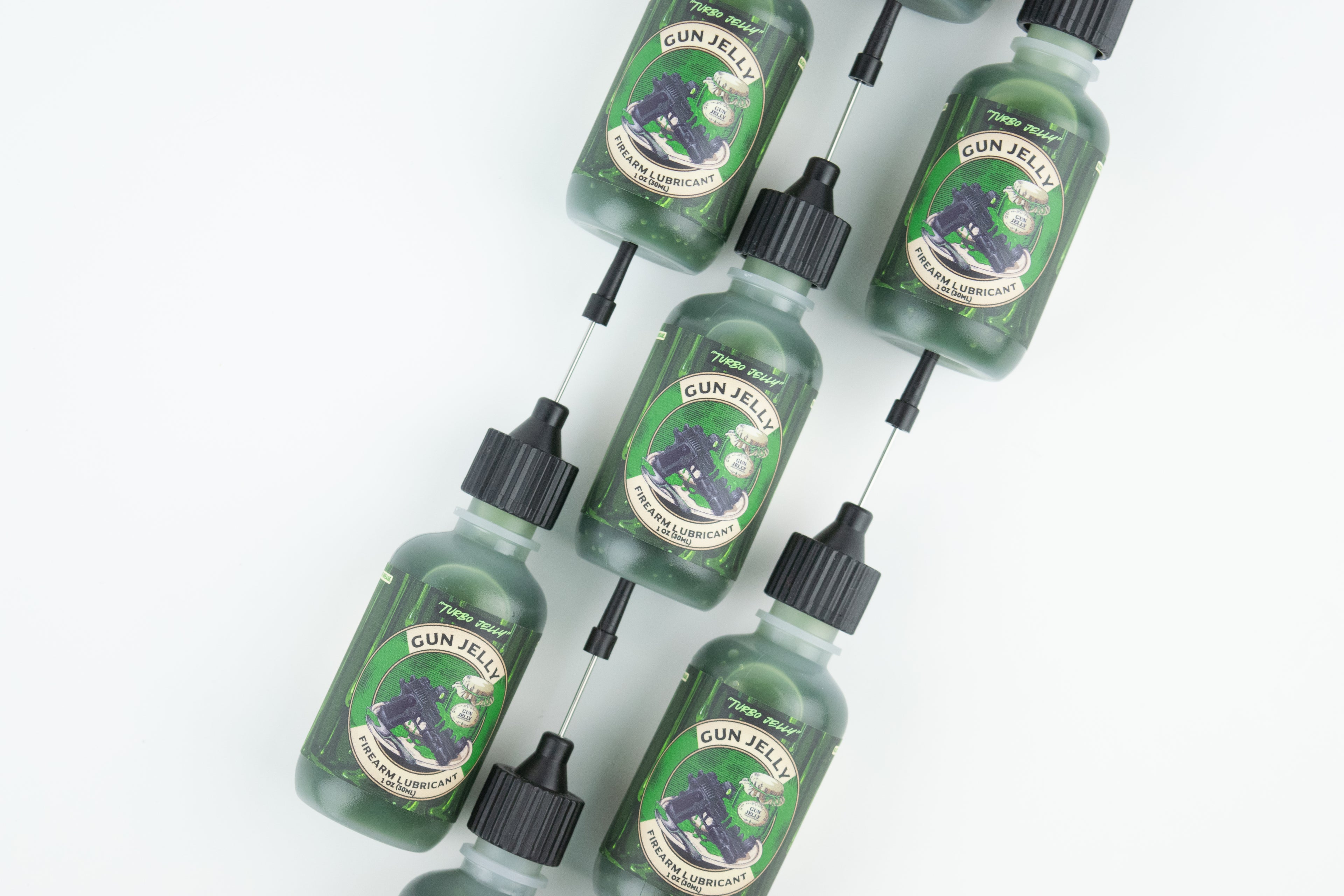 Six small green bottles of 'Turbo Jelly' Firearm Lubricant with black caps and arranged diagonally on a clean white background.